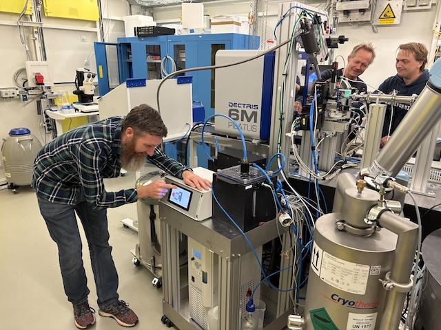 Several people are working in a modern laboratory on a complex X-ray crystallography setup.