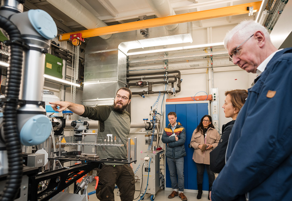 A scientist explains a complex experimental setup to an interested group of people.