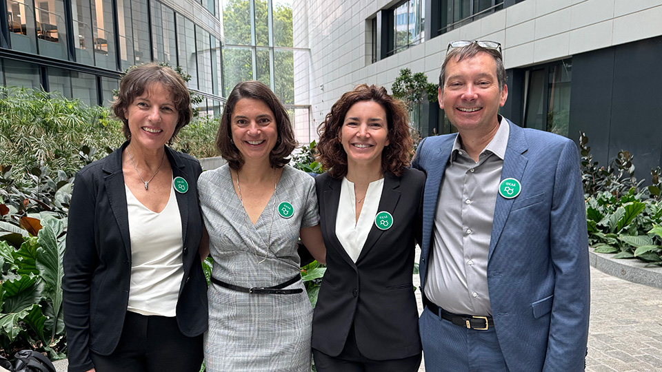 Four smiling people stand in a brightly lit foyer.