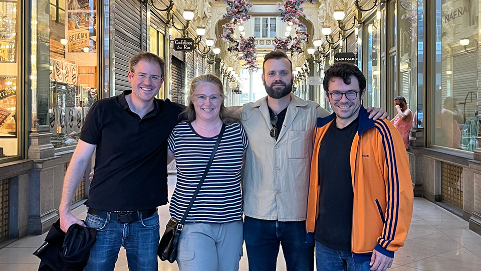 Four smiling people stand in a brightly lit foyer.