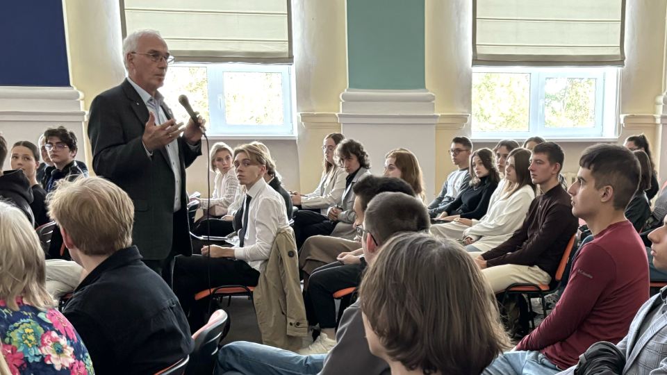 Helmut Dosch speaking with a microphone to a group of young people in a seminar room.