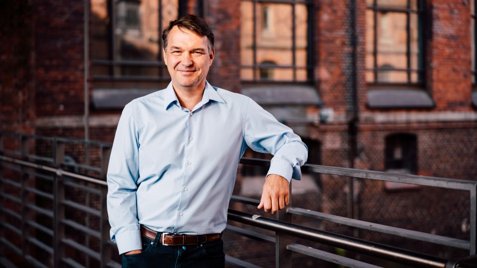 Jens Schröder bei einem Portrait im Außenbereich eines Backsteingebäudes mit Industriecharakter.