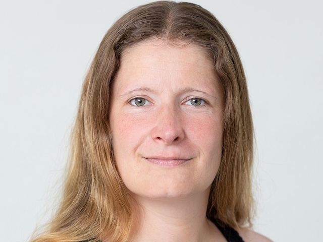 Portrait einer lächelnden Frau mit offenen, hellbraunen Haaren.