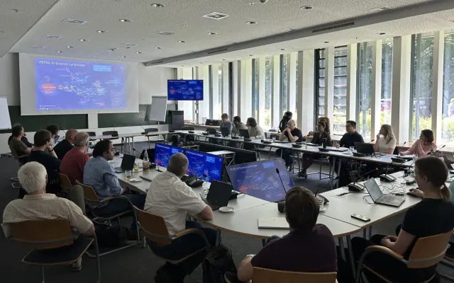Researchers discuss scientific data in a modern conference room with presentation screens and laptops.