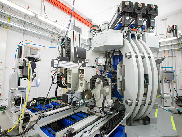 A complex scientific apparatus with cables sitting on rails in a white lab environment.