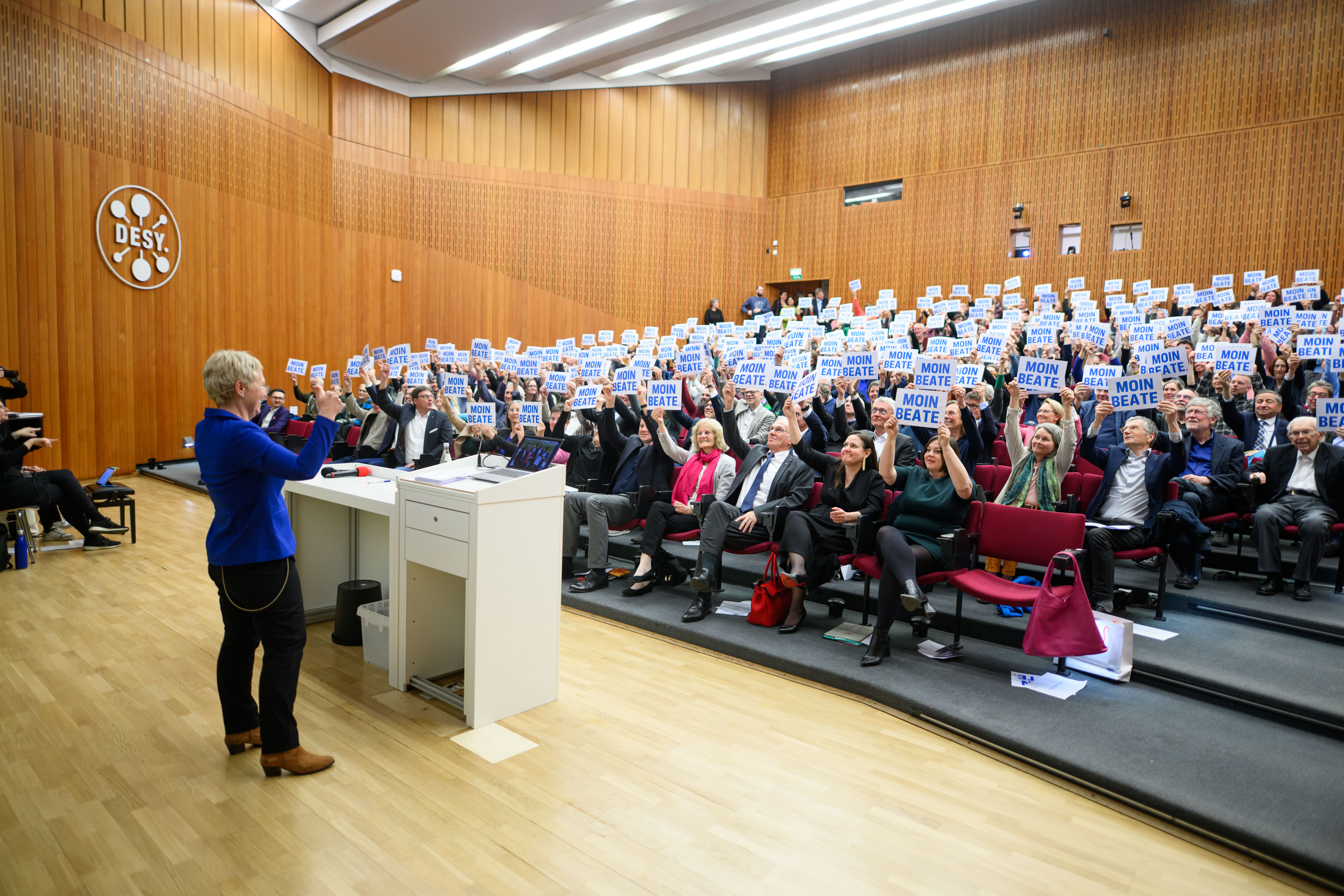 Viele Menschen sitzen und halten Schild hoch