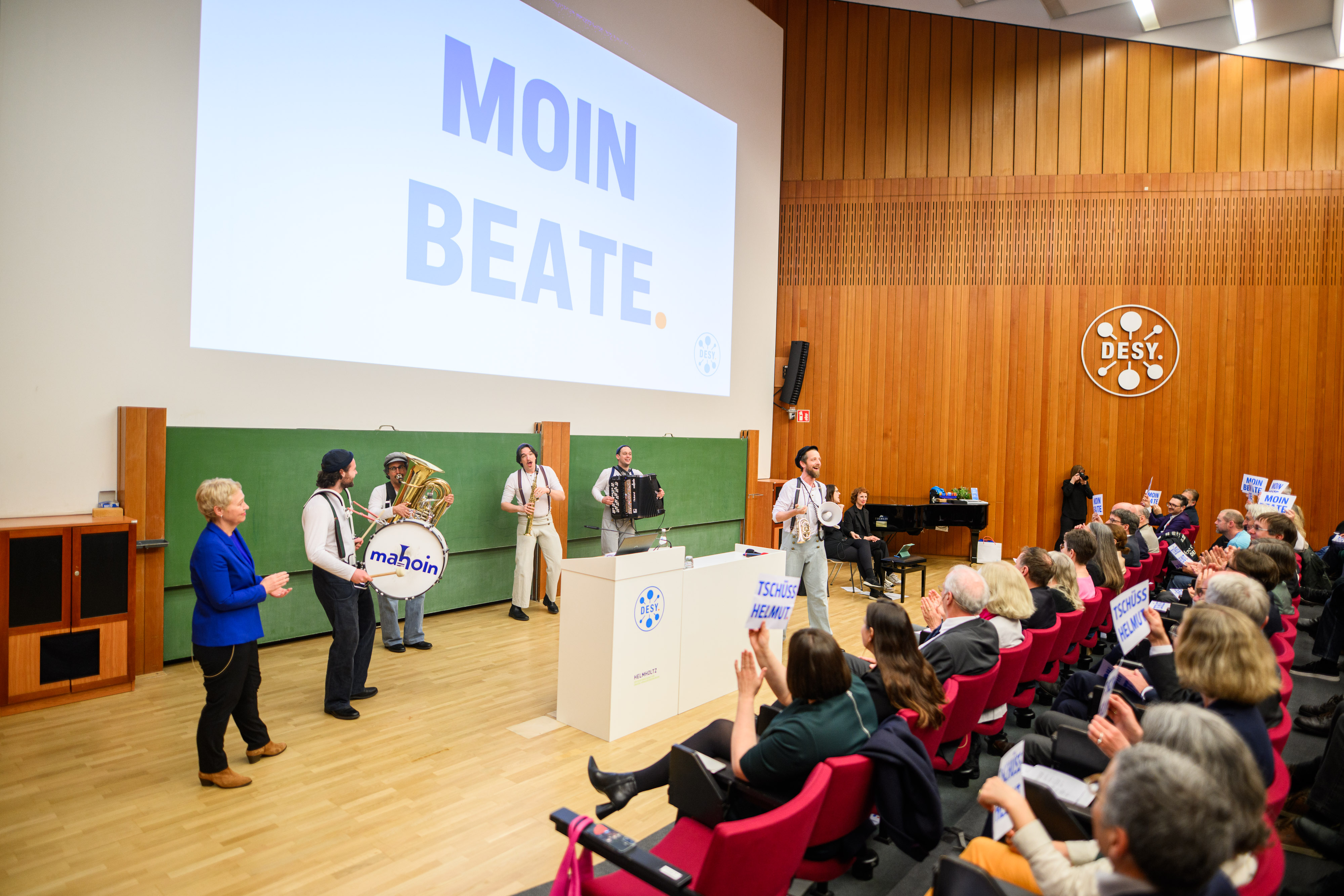 Eine Truppe Musiker mit Trommel und Bläsern steht auf der Bühne