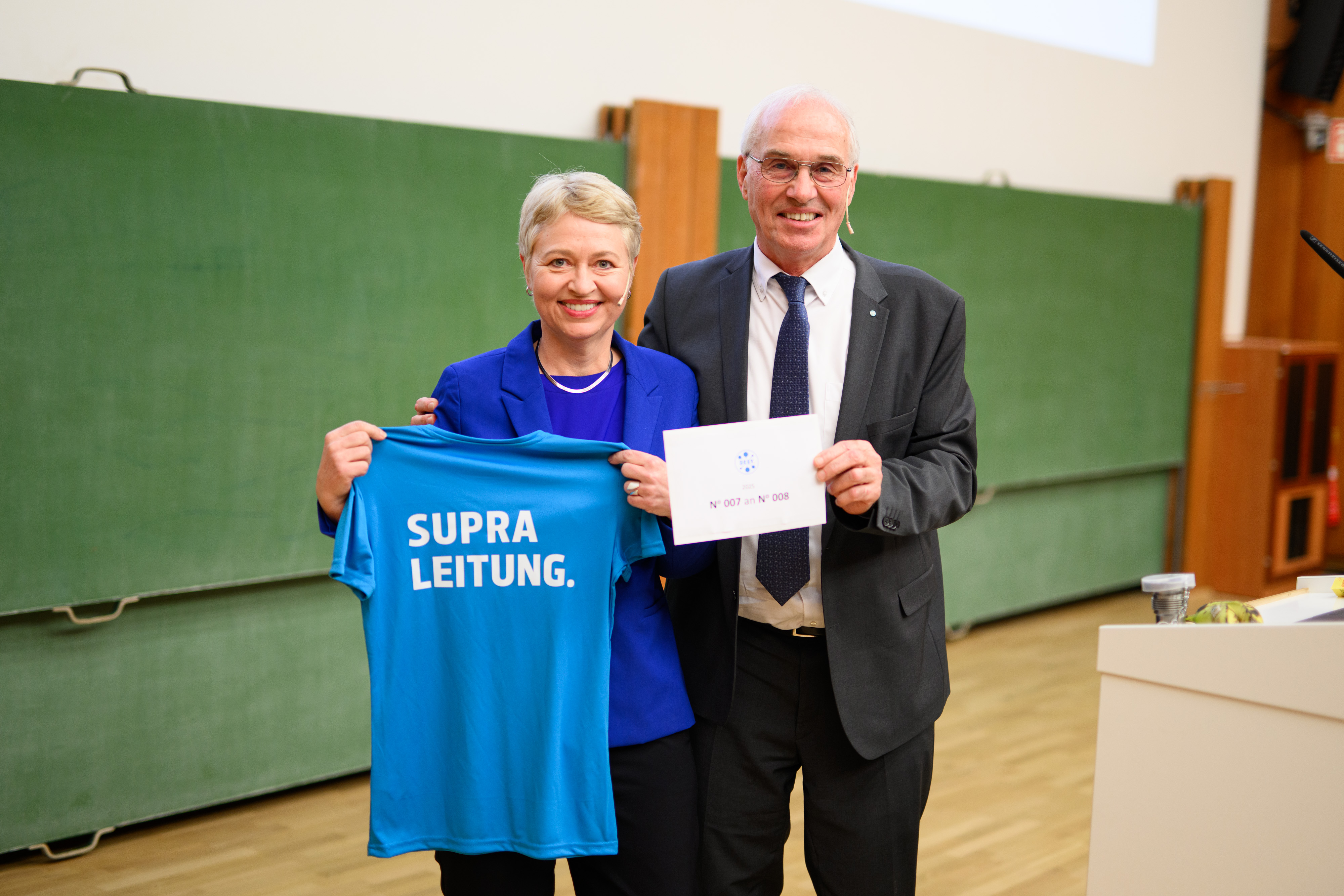Frau hält T-shirt hoch, Mann einen Brief. Frau hält T-shirt hoch, Mann einen Brief.