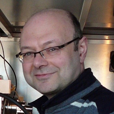 Freundlich blickender Mann mit Brille und schütterem Haar im Labor.