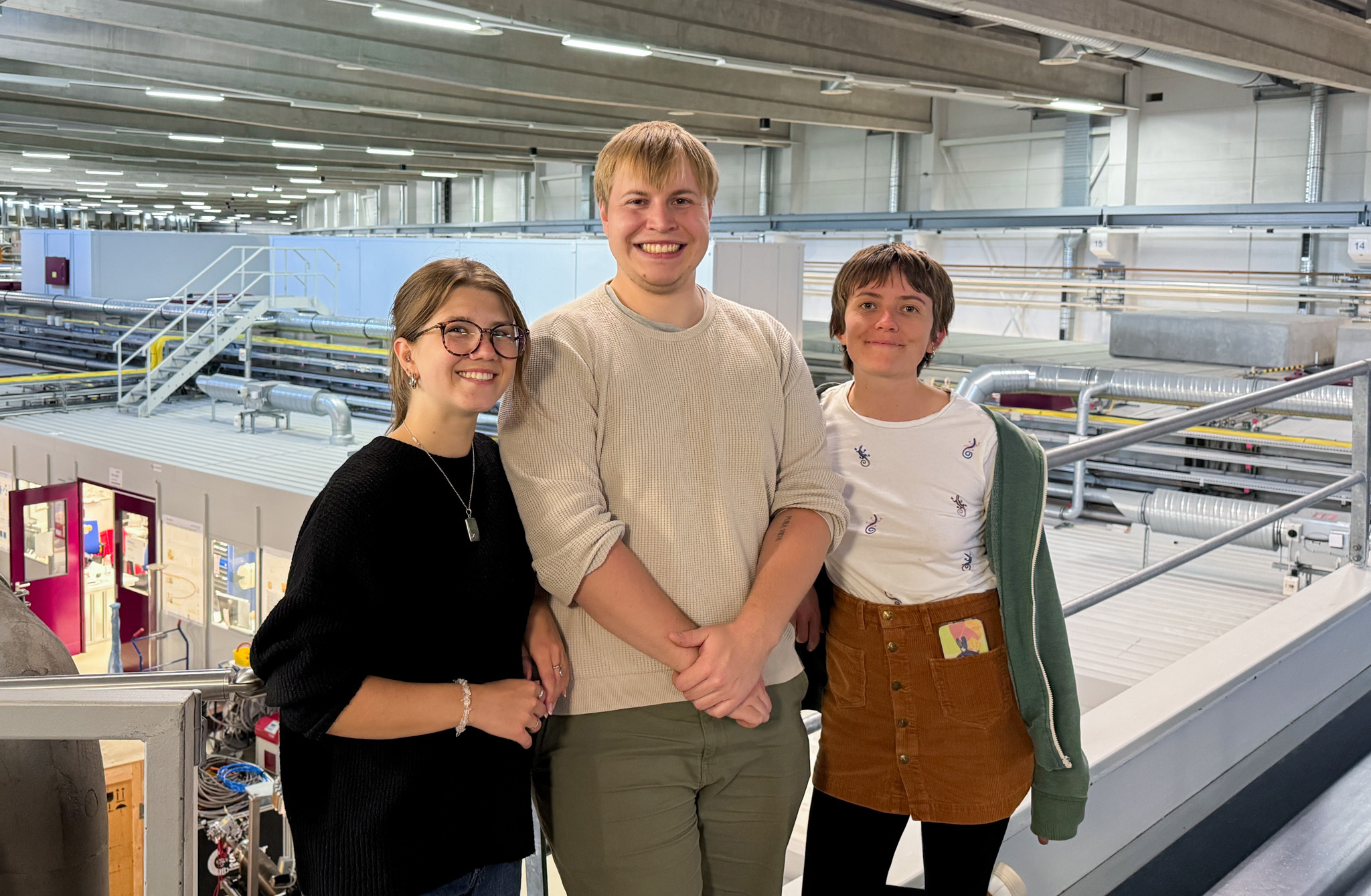 Drei Personen stehen in einer großen Halle